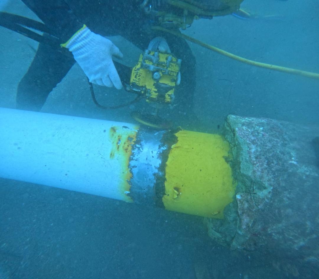 Buzo trabajando con una herramienta sobre una tubería submarina